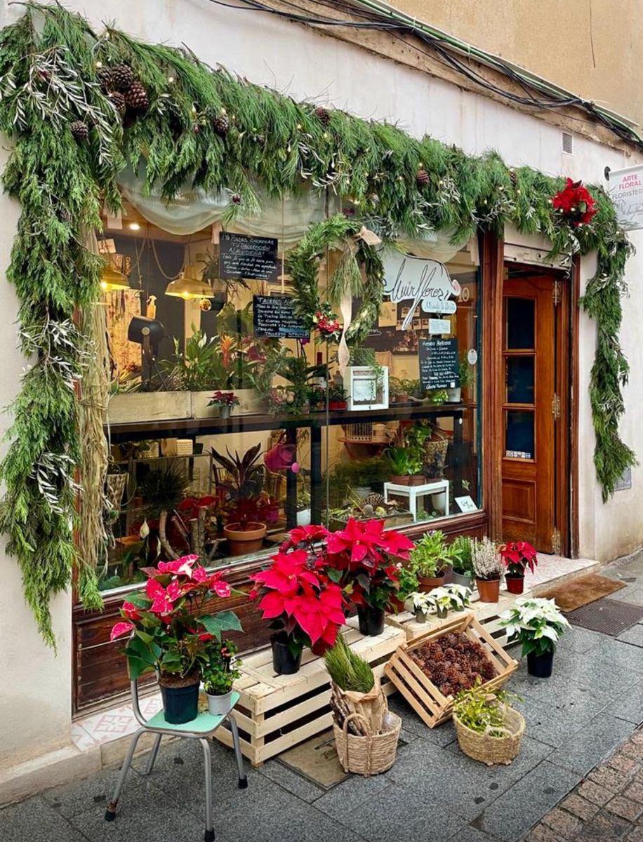 Fachada de la floristería MirFlores con guirnalda navideña y flores de pascua en la puerta