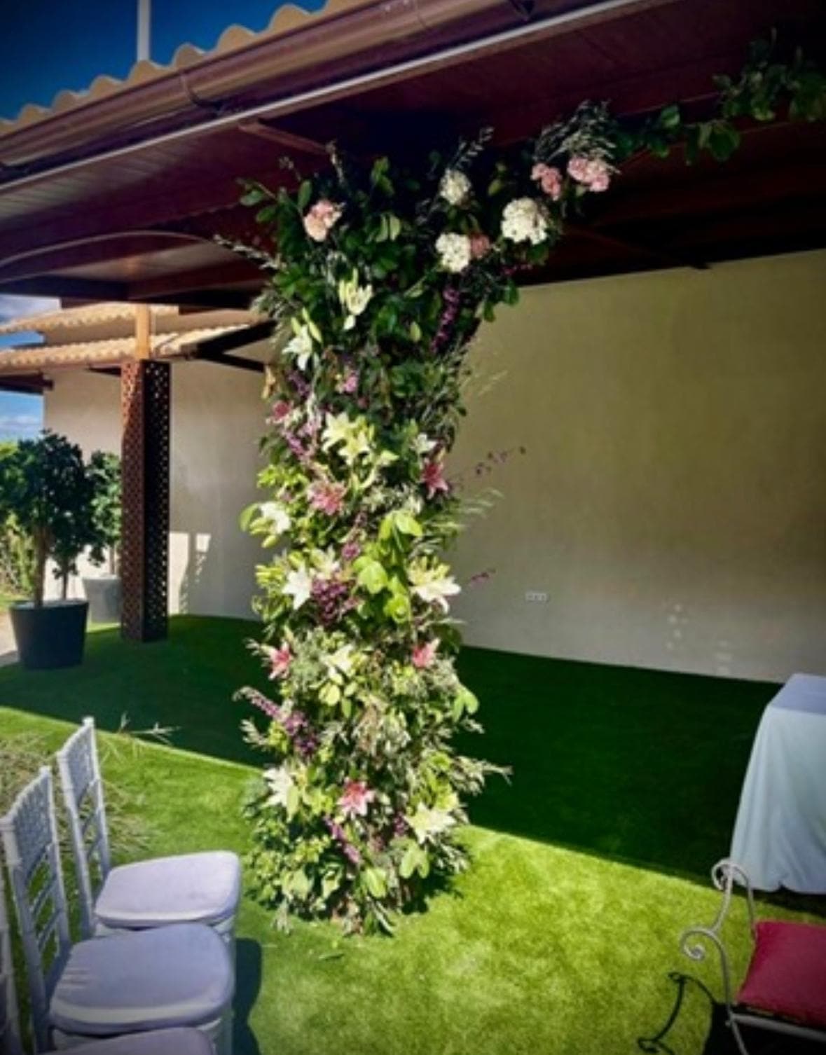 Columna floral de rosas y lirios sobre pérgola de madera para ceremonia de boda