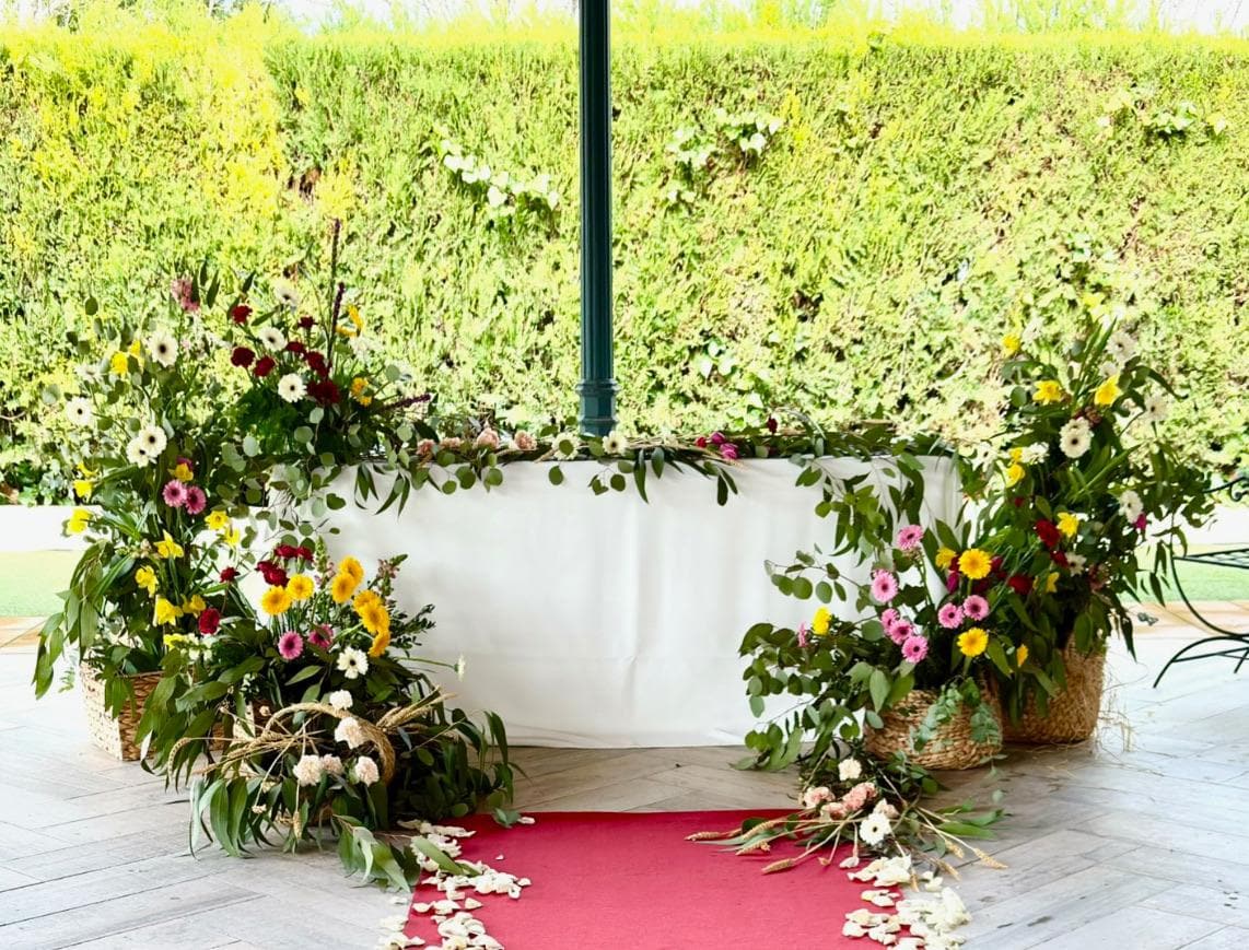 Mesa ceremonial decorada con gerberas de colores y alfombra roja