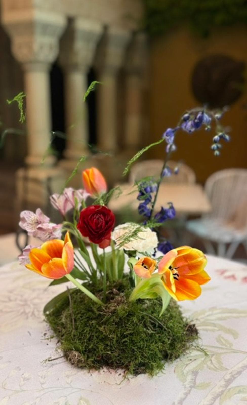 Mini centro de mesa con tulipanes naranjas, rosa roja y musgo