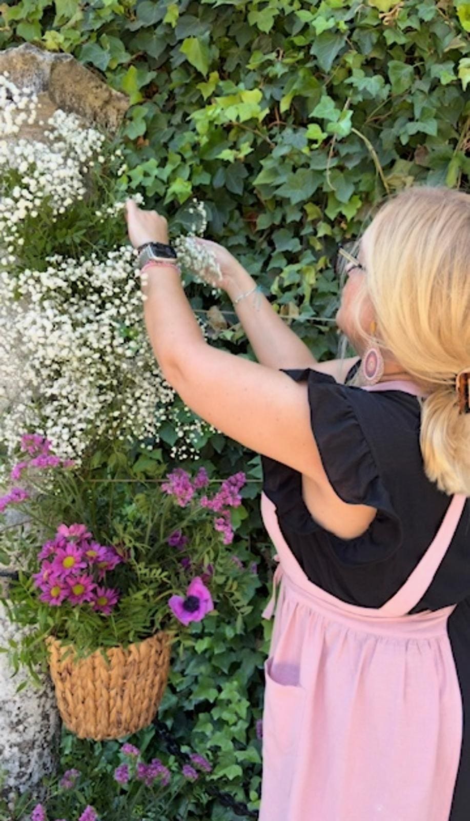 Miriam, la chica de las flores, colocando gypsophila y flores moradas en un montaje floral